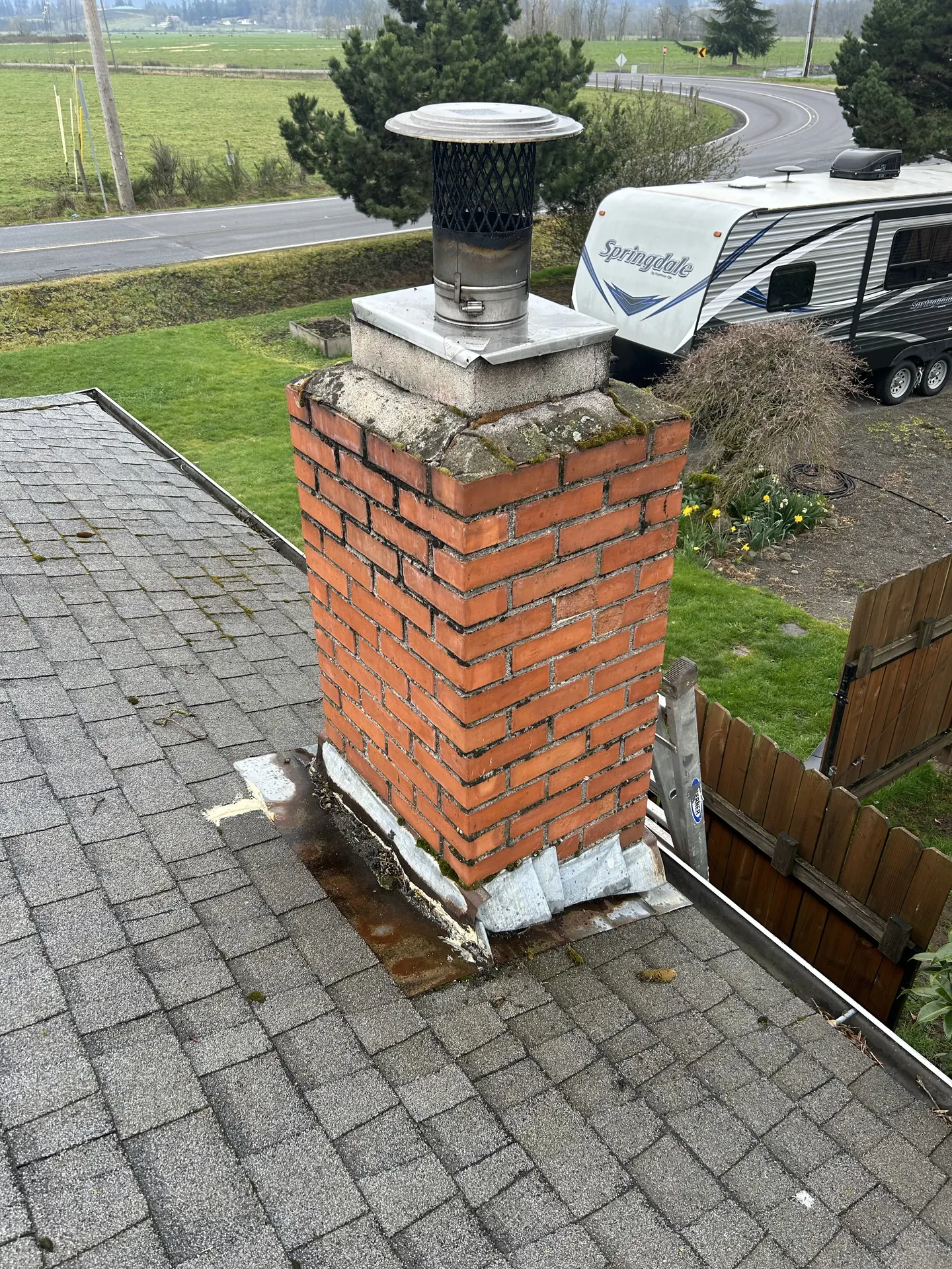 The same Estacada chimney before its rebuild: a mossy, cracked crown and failing step flashing