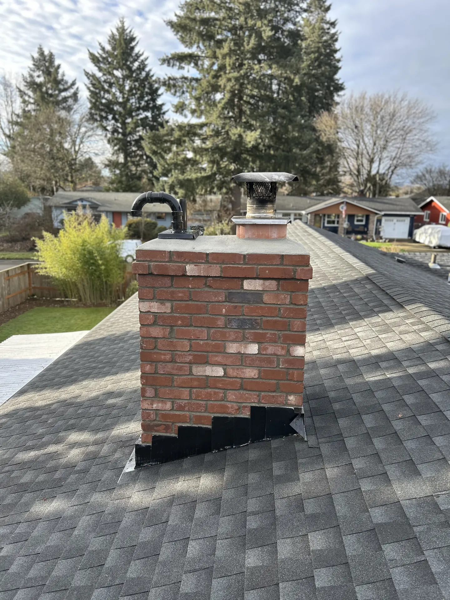 A First Rate Chimney rooftop photo of a brick chimney with a pellet stove vent in the Estacada area