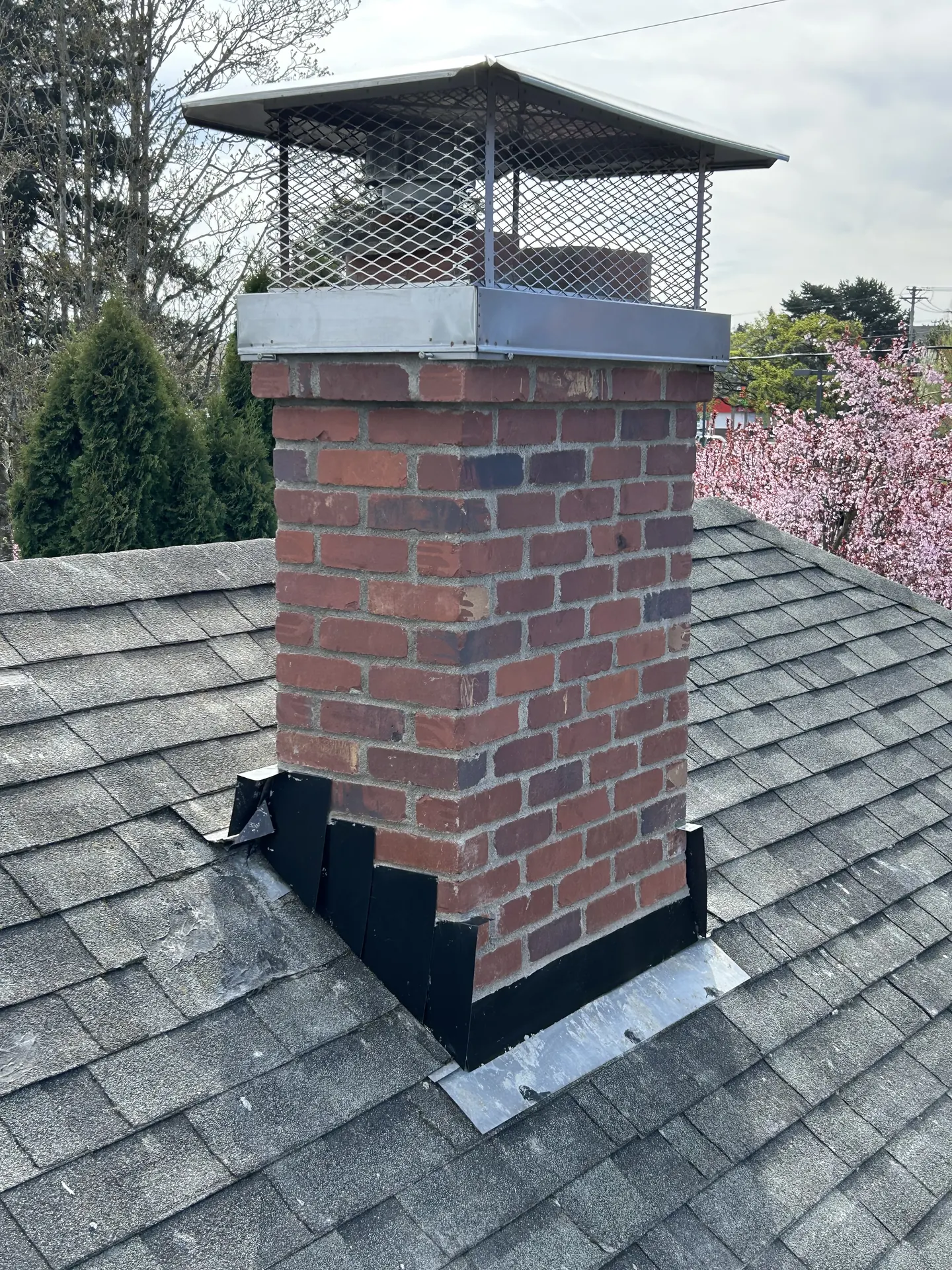 A custom black powder-coated chimney cap installed by First Rate Chimney on a brick chimney