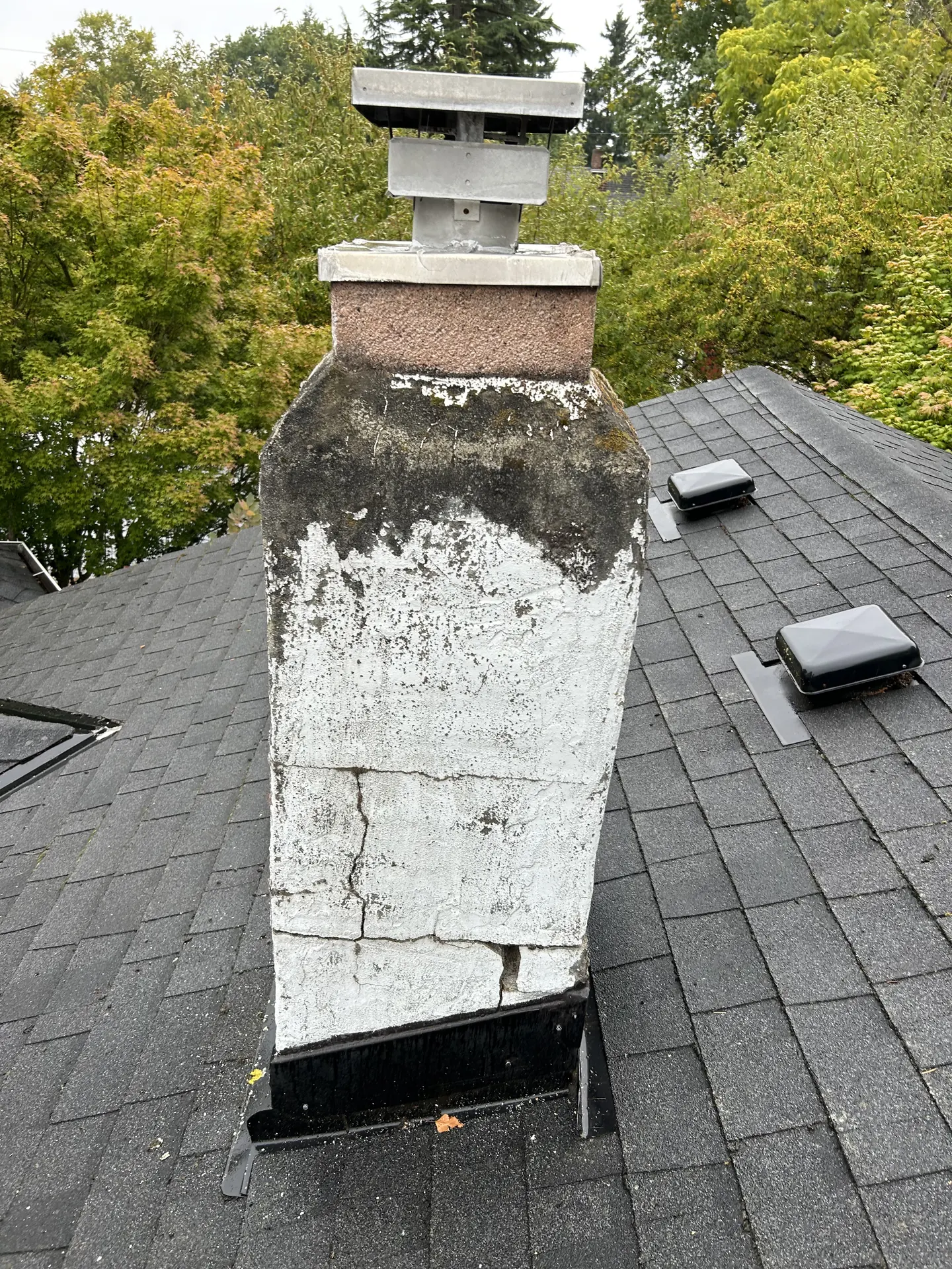 Cracked white-painted chimney with failing mortar before the rebuild